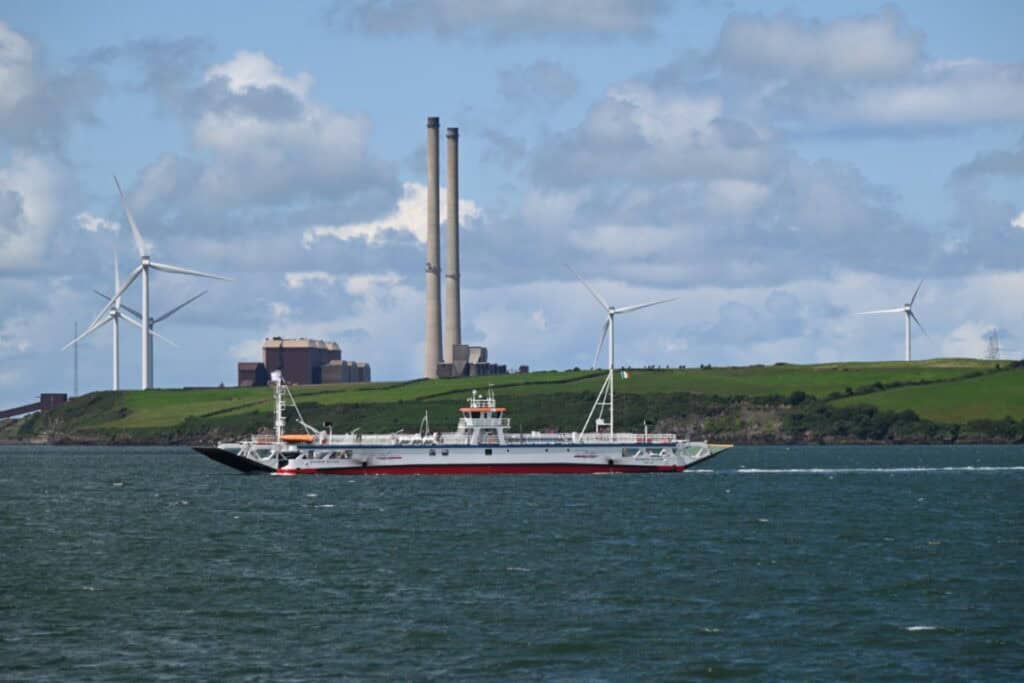 Boat sailing from Dingle Bay towards Dublin with wind turbines in the background.