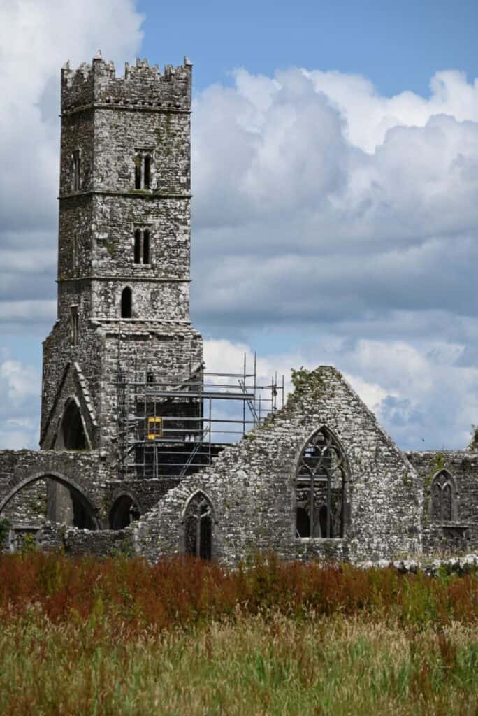 Ancient stone church ruins with a tall tower along the Dingle to Dublin route, showcasing Irish heri.