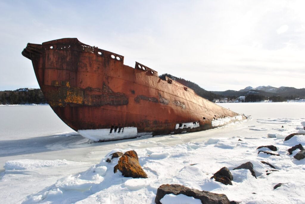Rusty shipwreck on icy shoreline in Conception Harbour, Newfoundland.