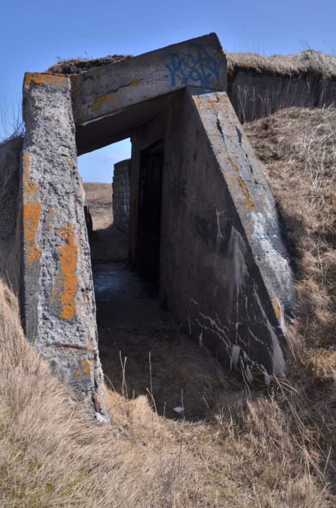 Abandoned concrete military bunker at Argentia Naval Air Station, surrounded by dry grass and clear.