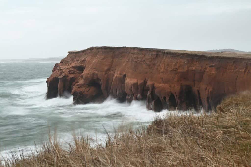 Cliffs of Îles-de-la-Madeleine with ocean waves crashing, in May.