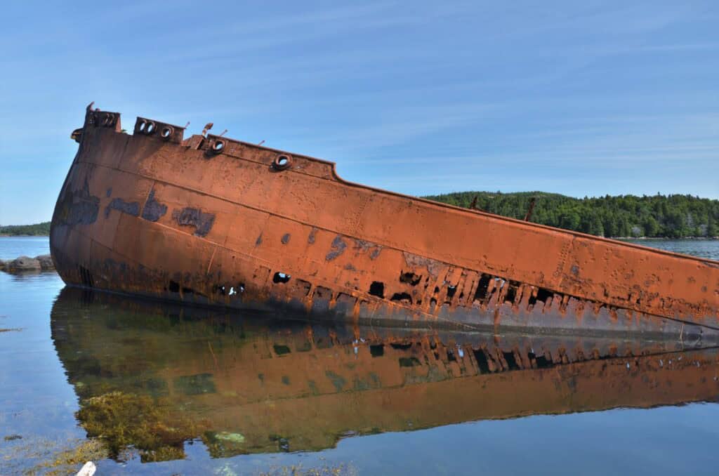 Wreck of an old shipwreck in Conception Harbour, Newfoundland and Labrador. Rusted hull partially su.