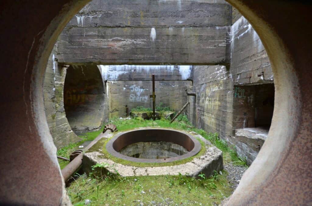 Historic mill equipment with concrete and metal components in an outdoor setting.