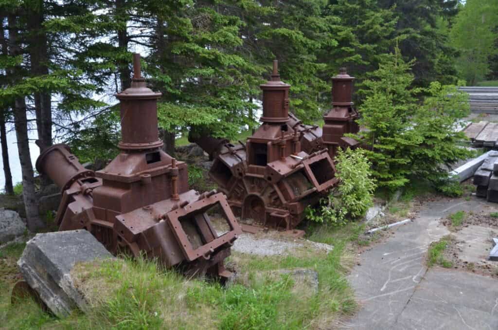 Old, abandoned lumber mill equipment surrounded by trees and greenery.