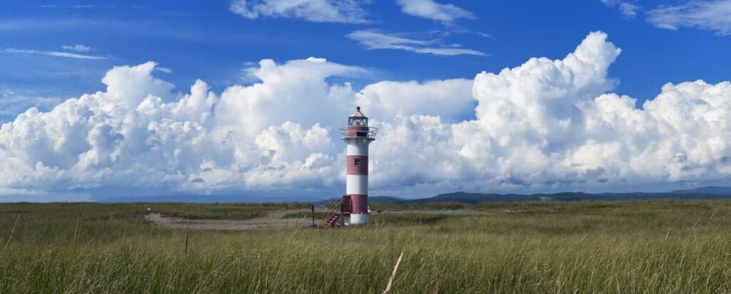 Lighthouse at Sandy Point with blue sky and clouds in the background.