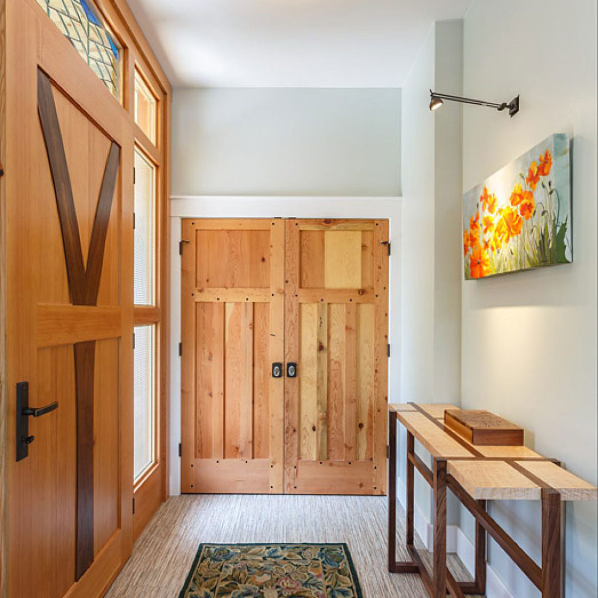 Interior view of a Craftsman-style home entrance with wooden doors and decor.