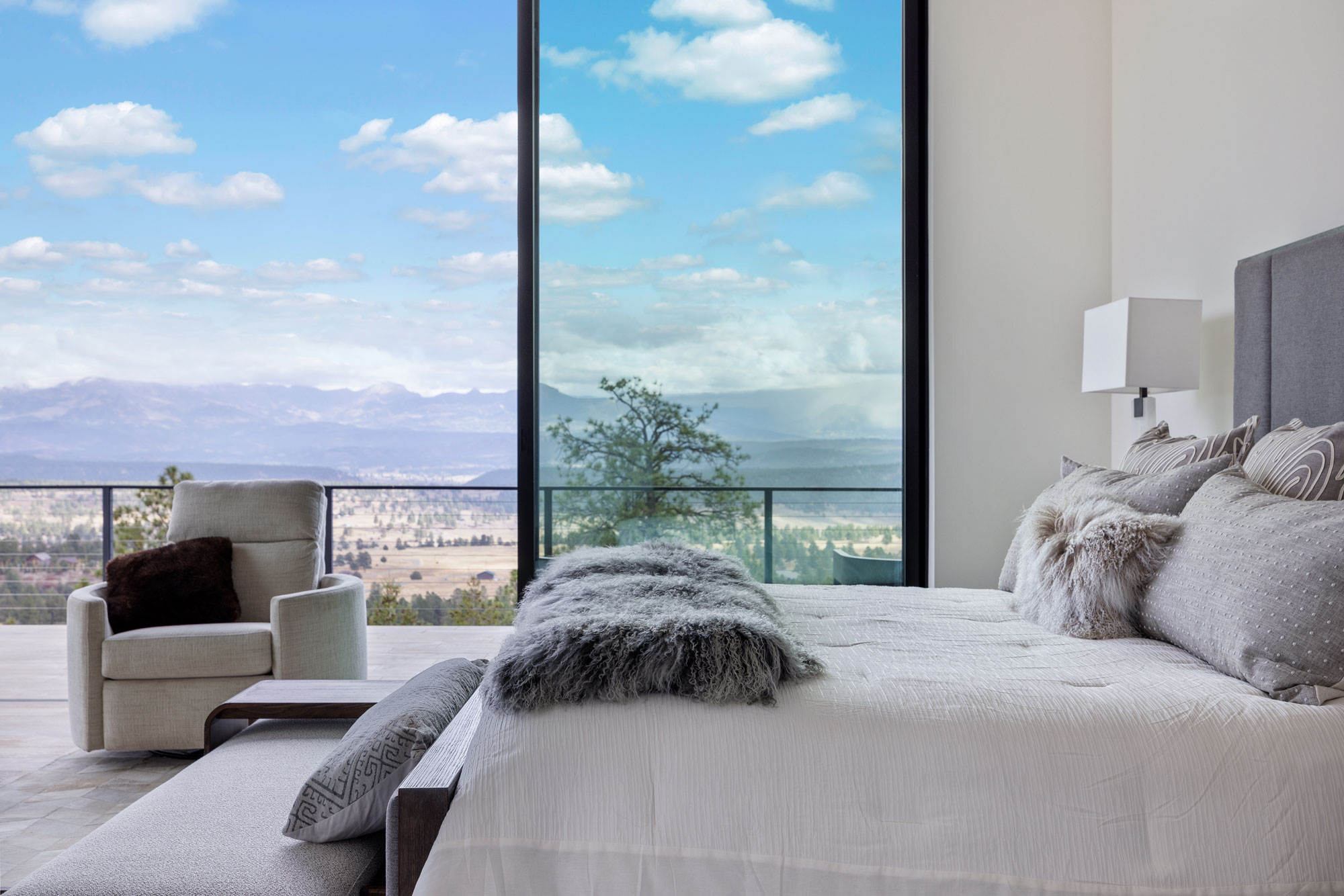 Spacious bedroom featuring floor-to-ceiling windows overlooking mountains and desert landscape.