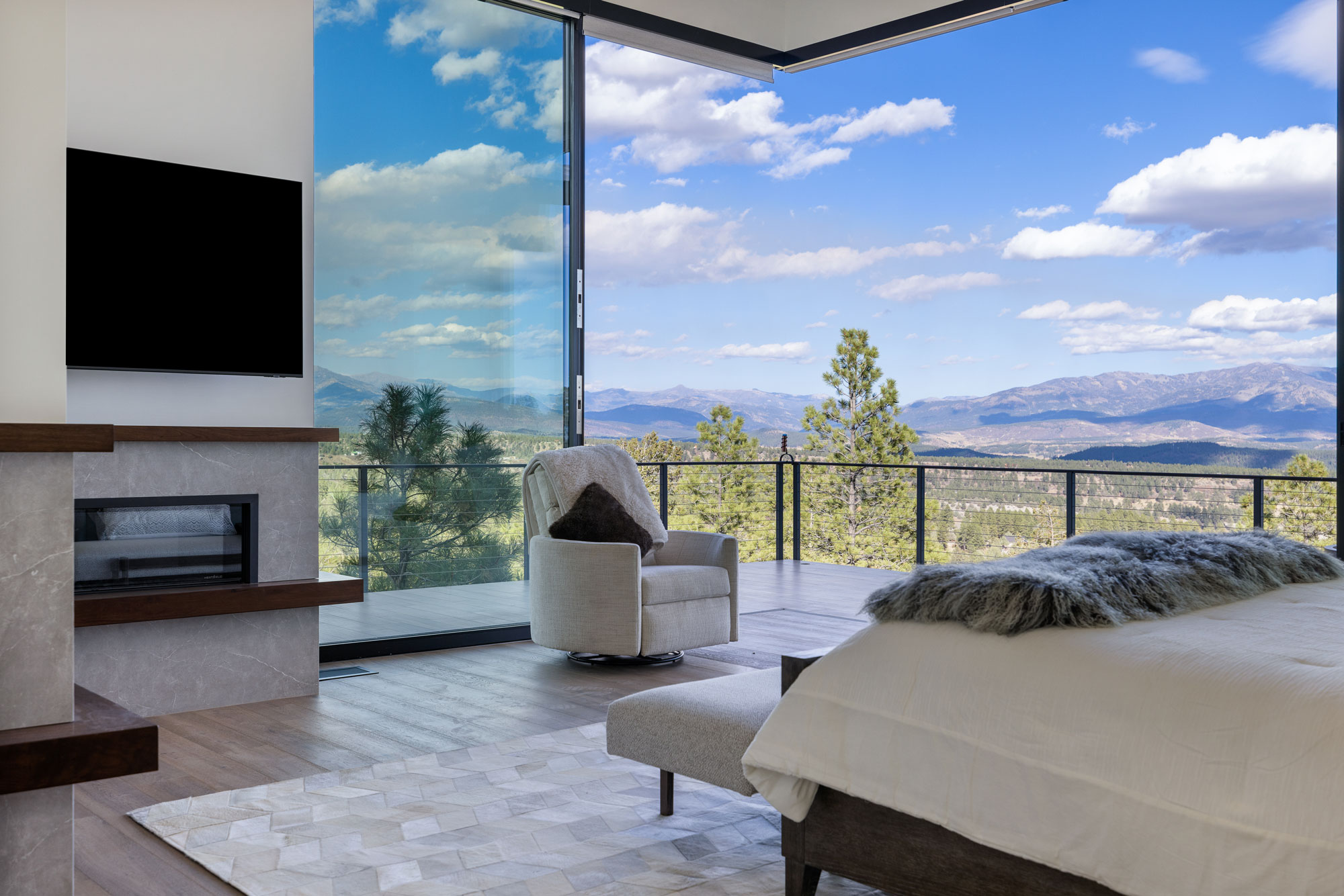 Spacious bedroom featuring large glass windows offering stunning mountain scenery and natural light.
