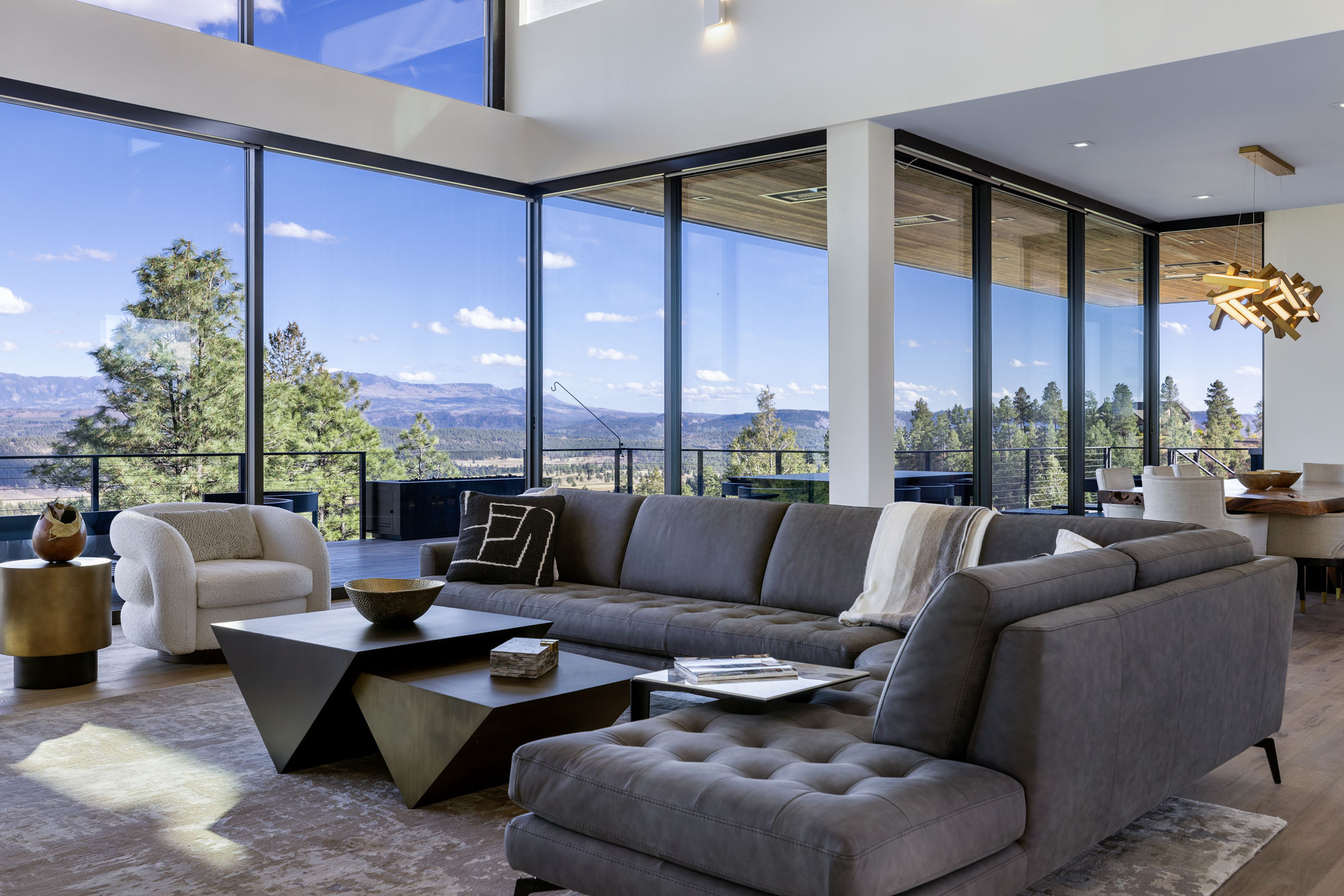 Spacious modern living room with large glass windows and scenic mountain views.