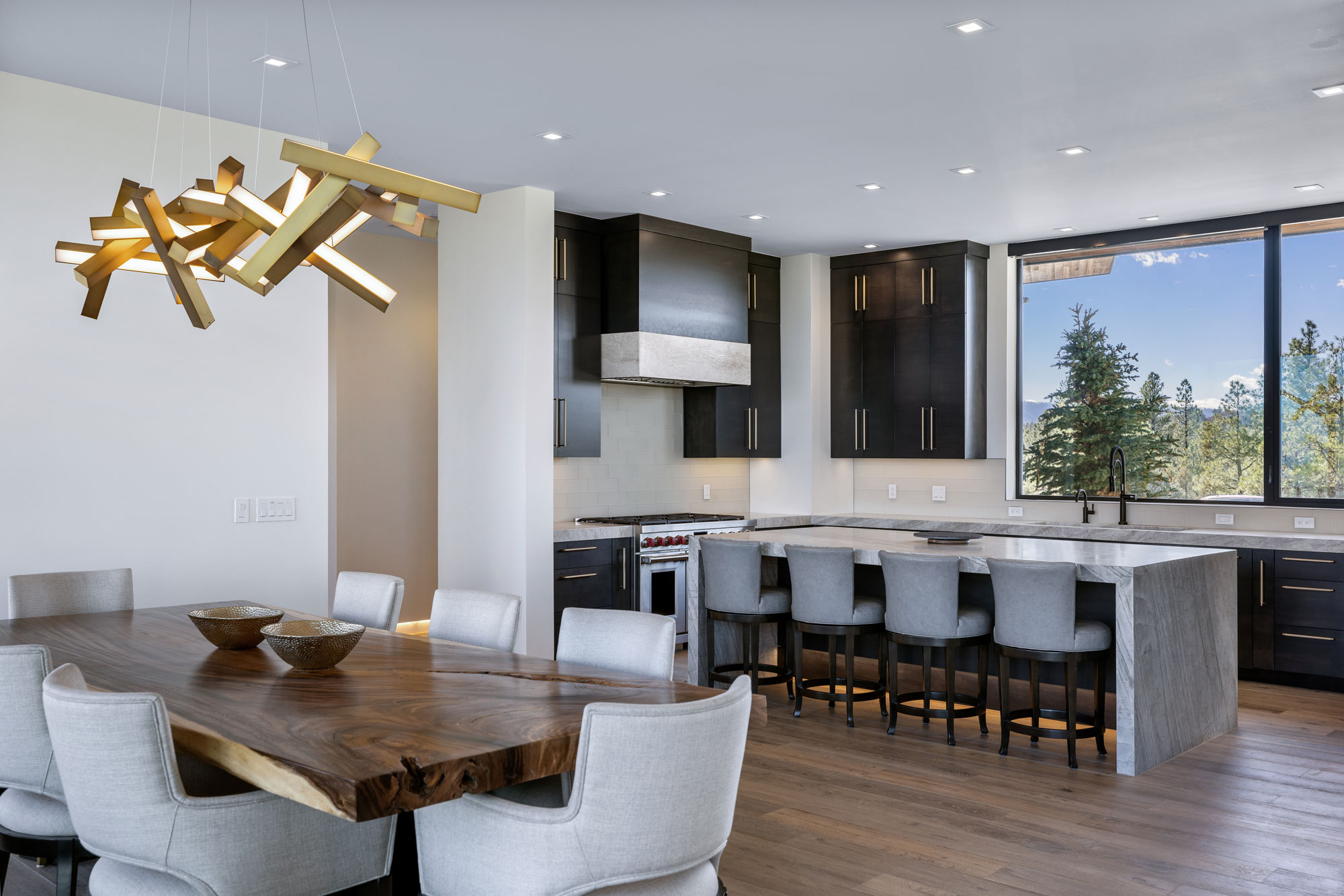 Modern kitchen and dining space with contemporary cabinetry, a large window, and stylish lighting fi.