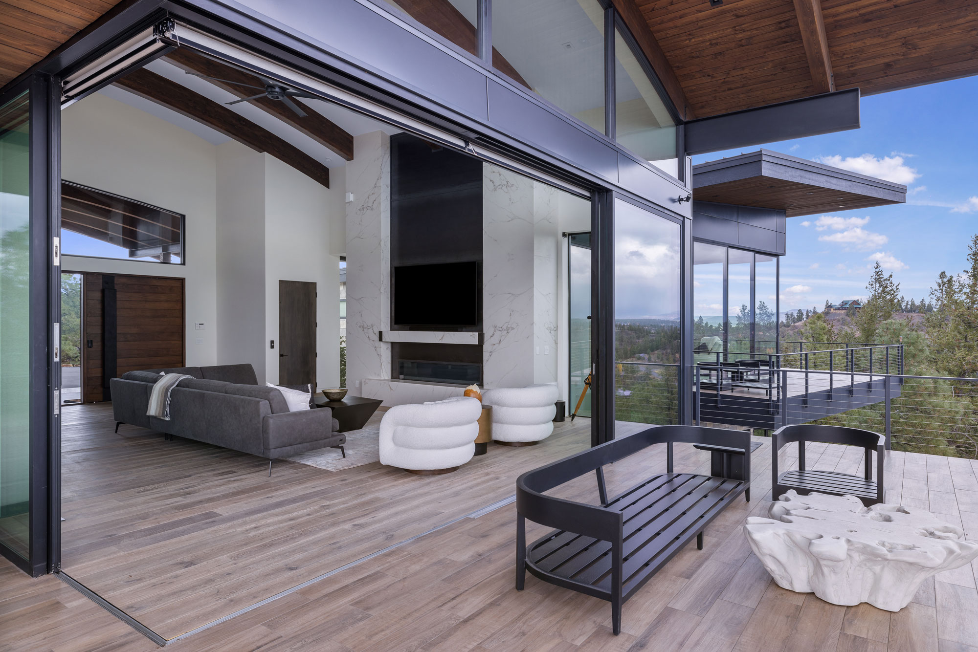 Spacious modern living room with floor-to-ceiling glass walls, contemporary furniture, and an outdoo.