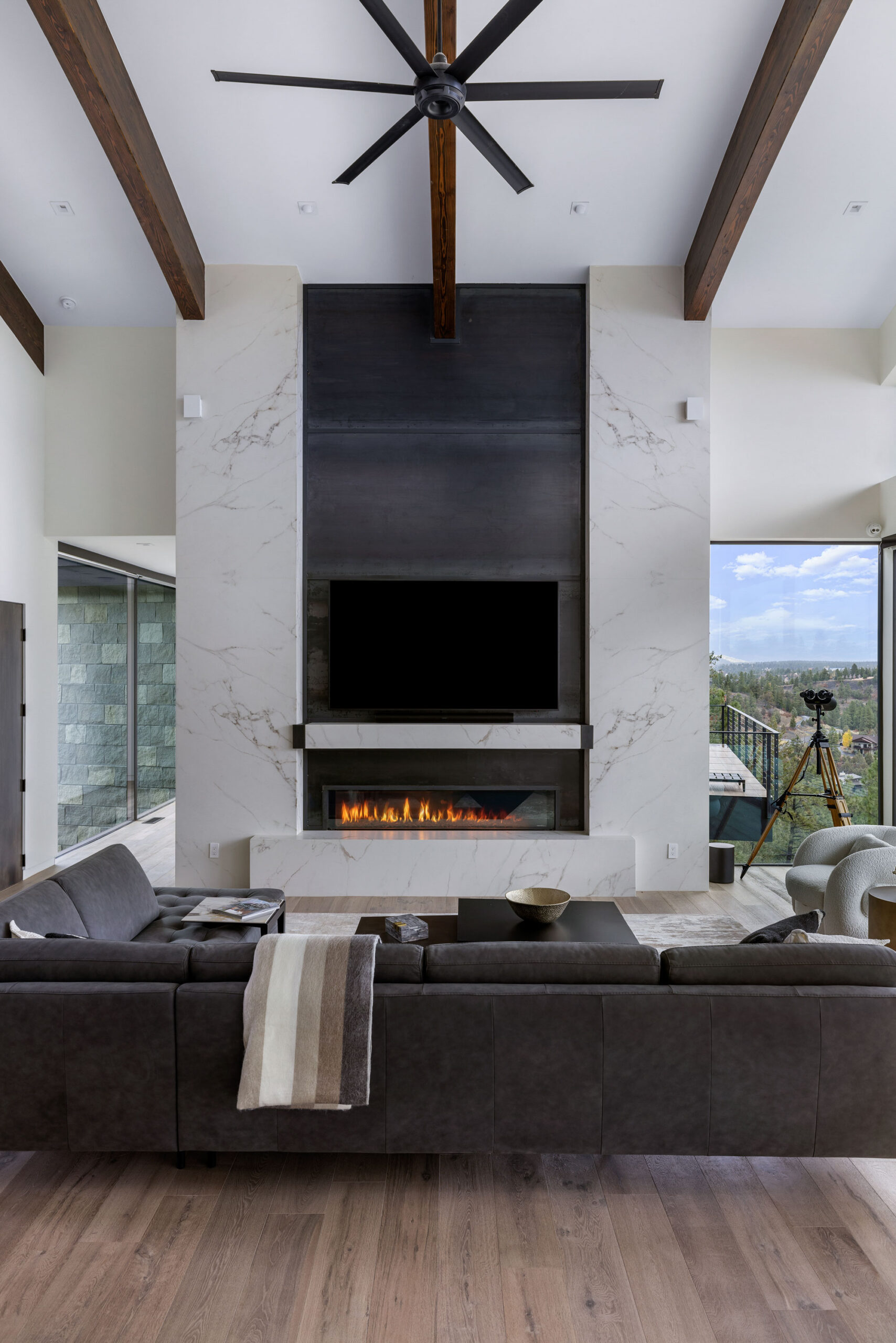 Fireplace and TV wall in a contemporary living room with high ceilings and wooden beams.