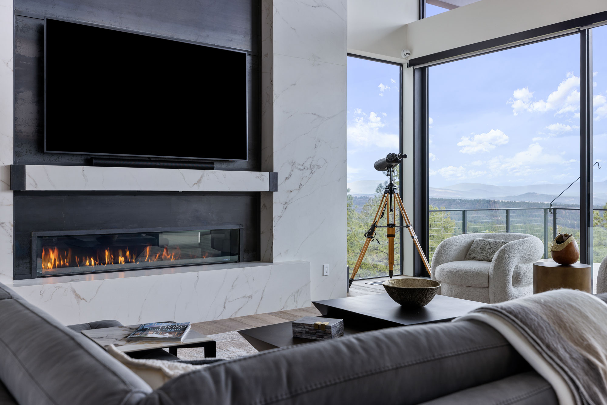 Modern living room with fireplace, telescope, and panoramic window view.