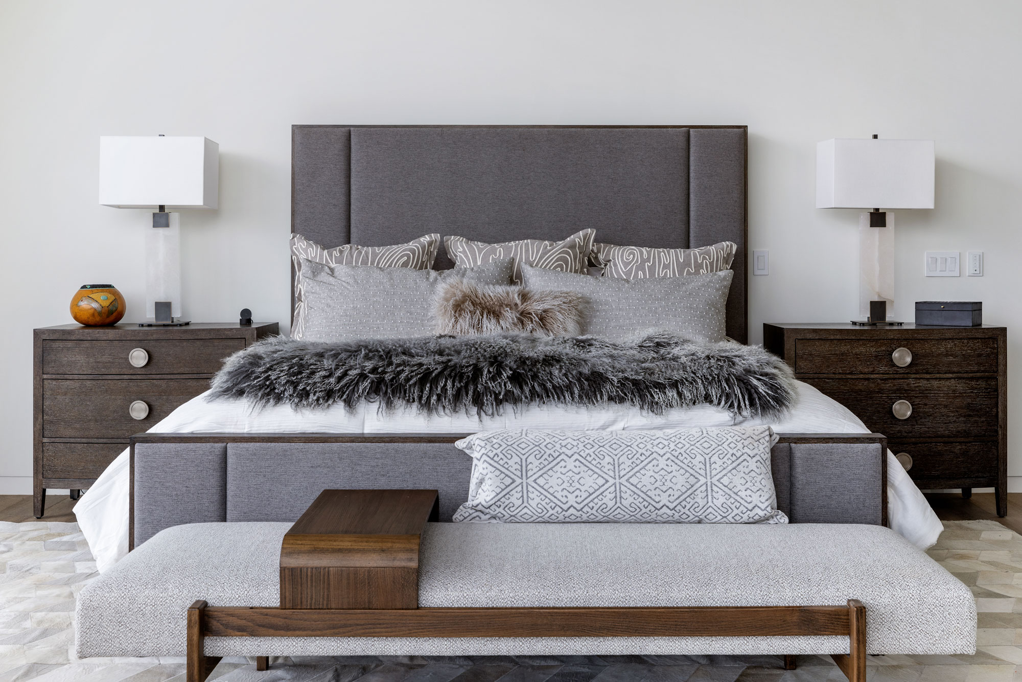 Bedroom interior with a large upholstered bed, nightstands, and decorative pillows.