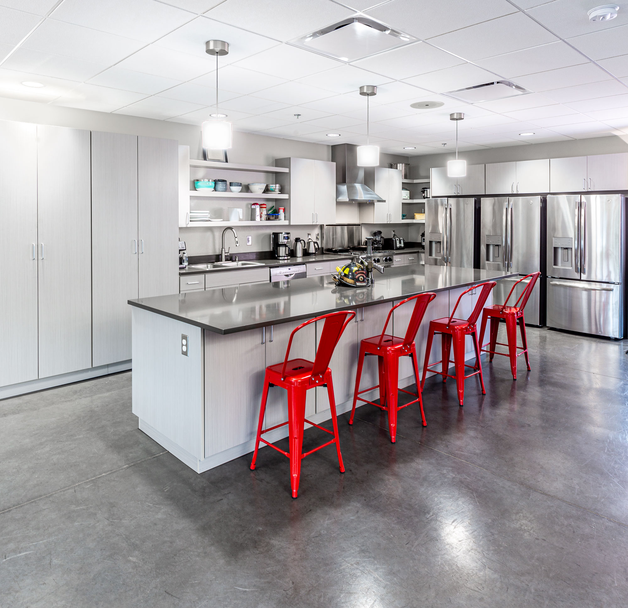Contemporary industrial kitchen with white cabinetry and red bar stools.