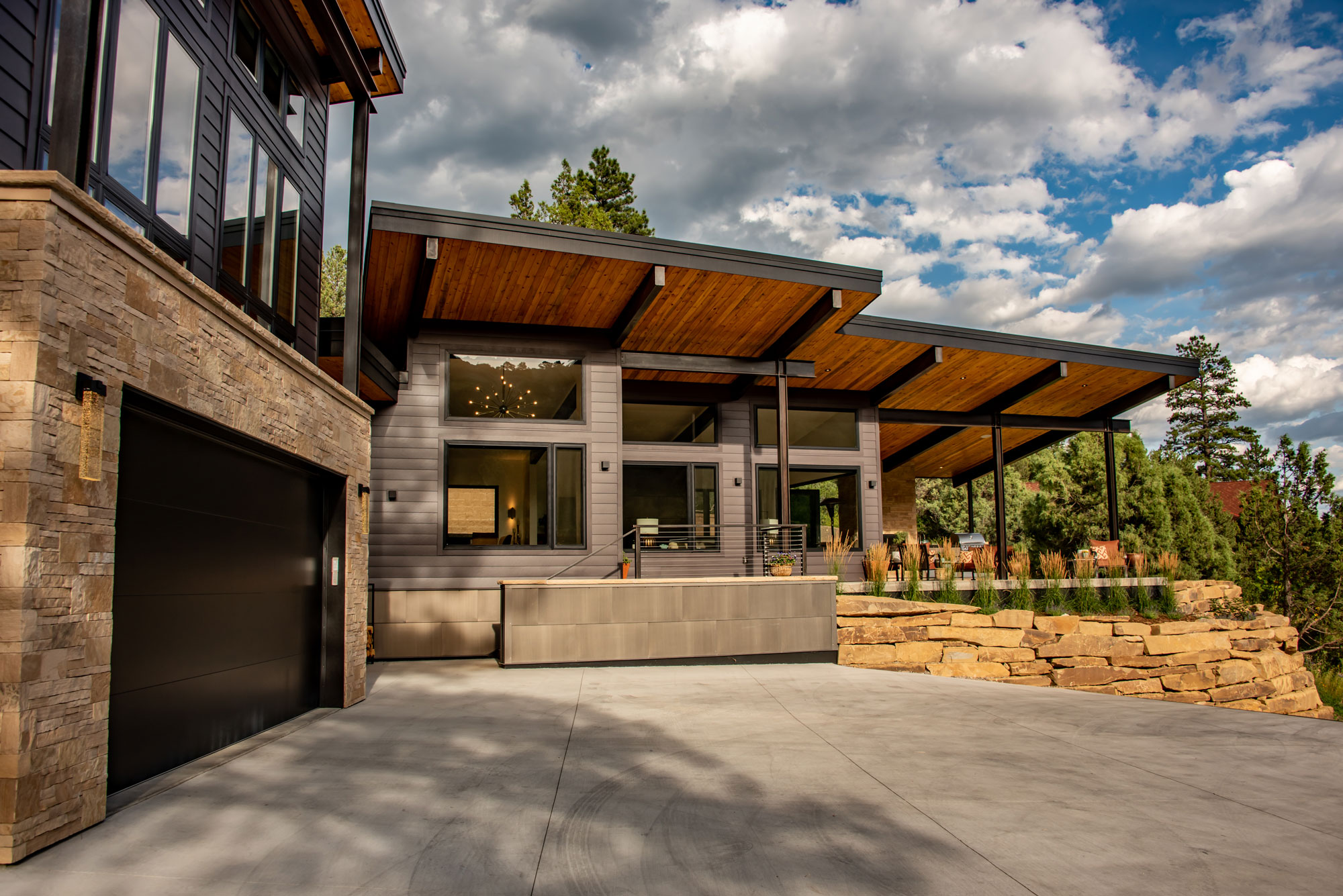 Contemporary house with large overhangs and stone accents in a scenic setting.