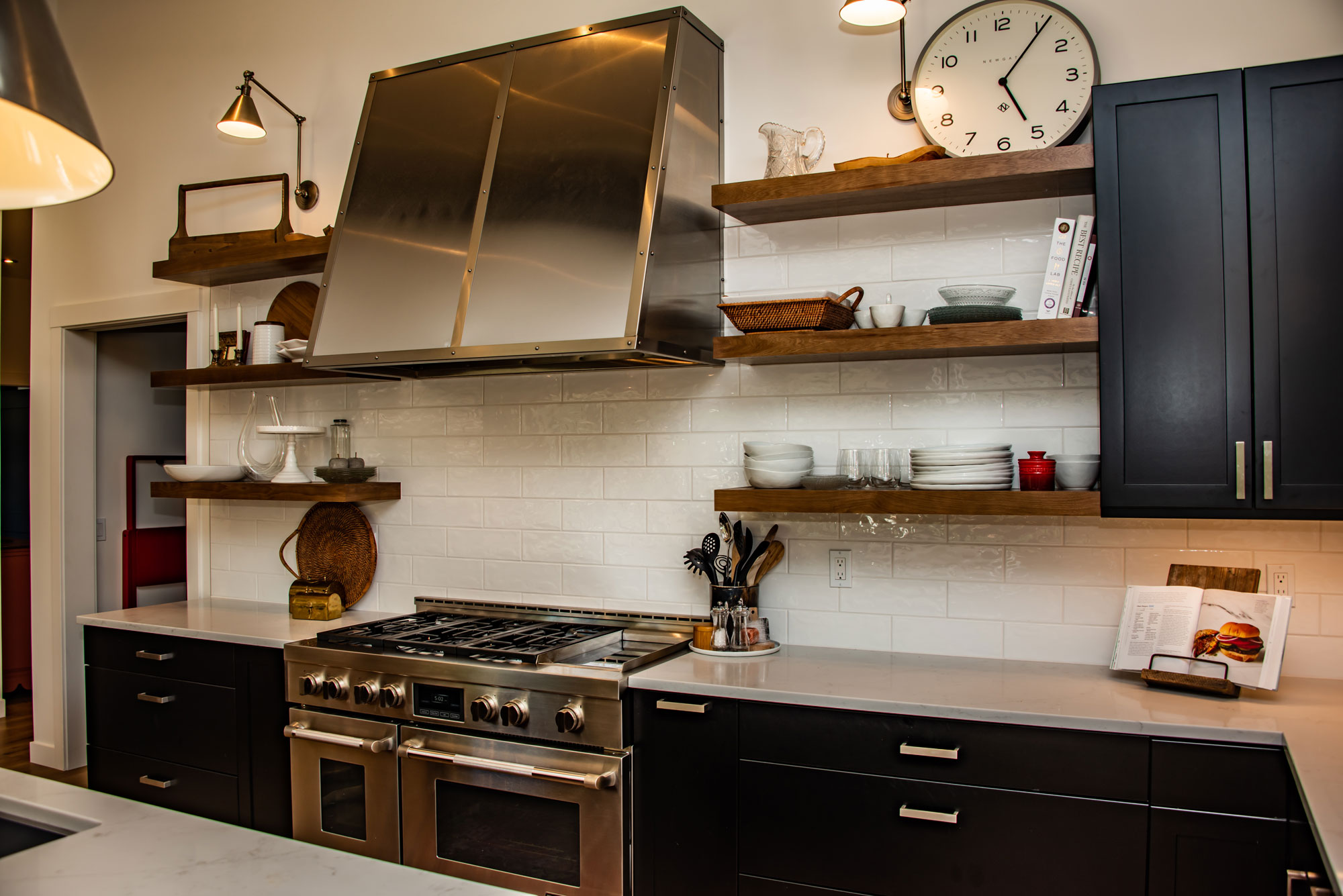 Contemporary kitchen with black cabinets, stainless steel appliances, and open shelving.