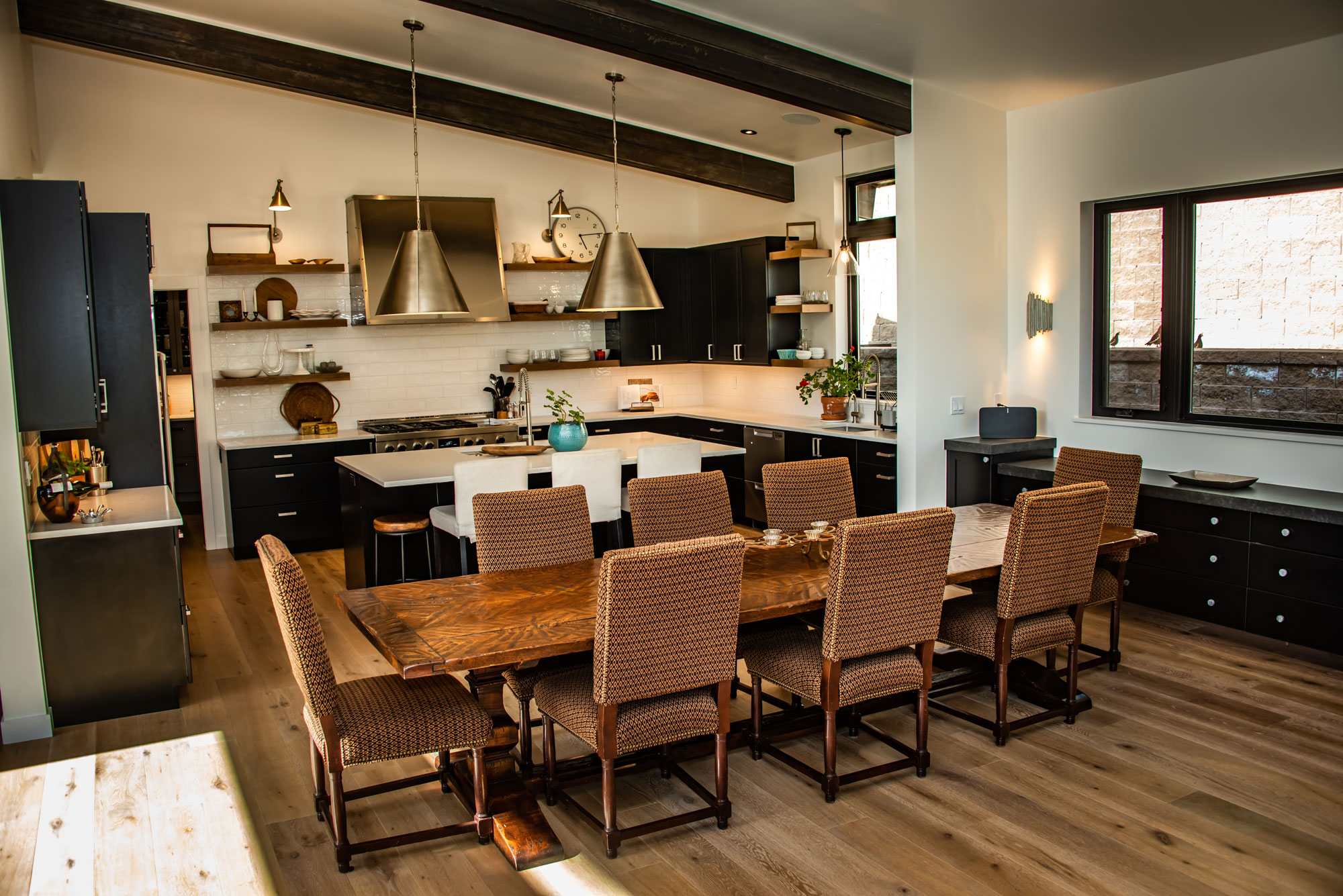 Spacious modern kitchen with wooden dining table and contemporary lighting fixtures.