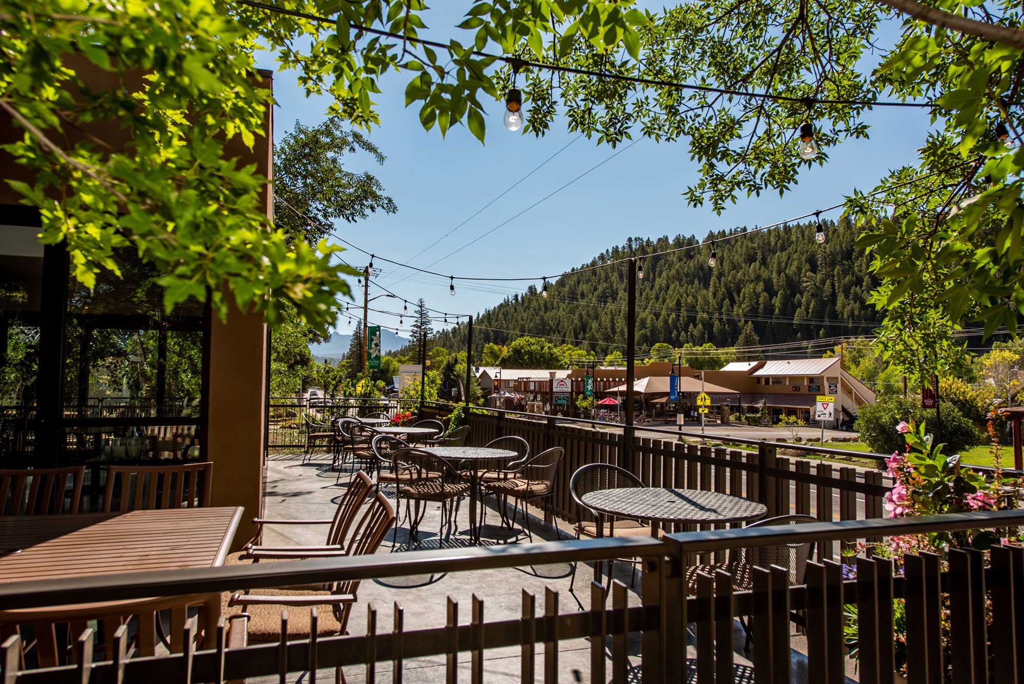 Outdoor dining area at Alley House Grille with tables and chairs under trees.