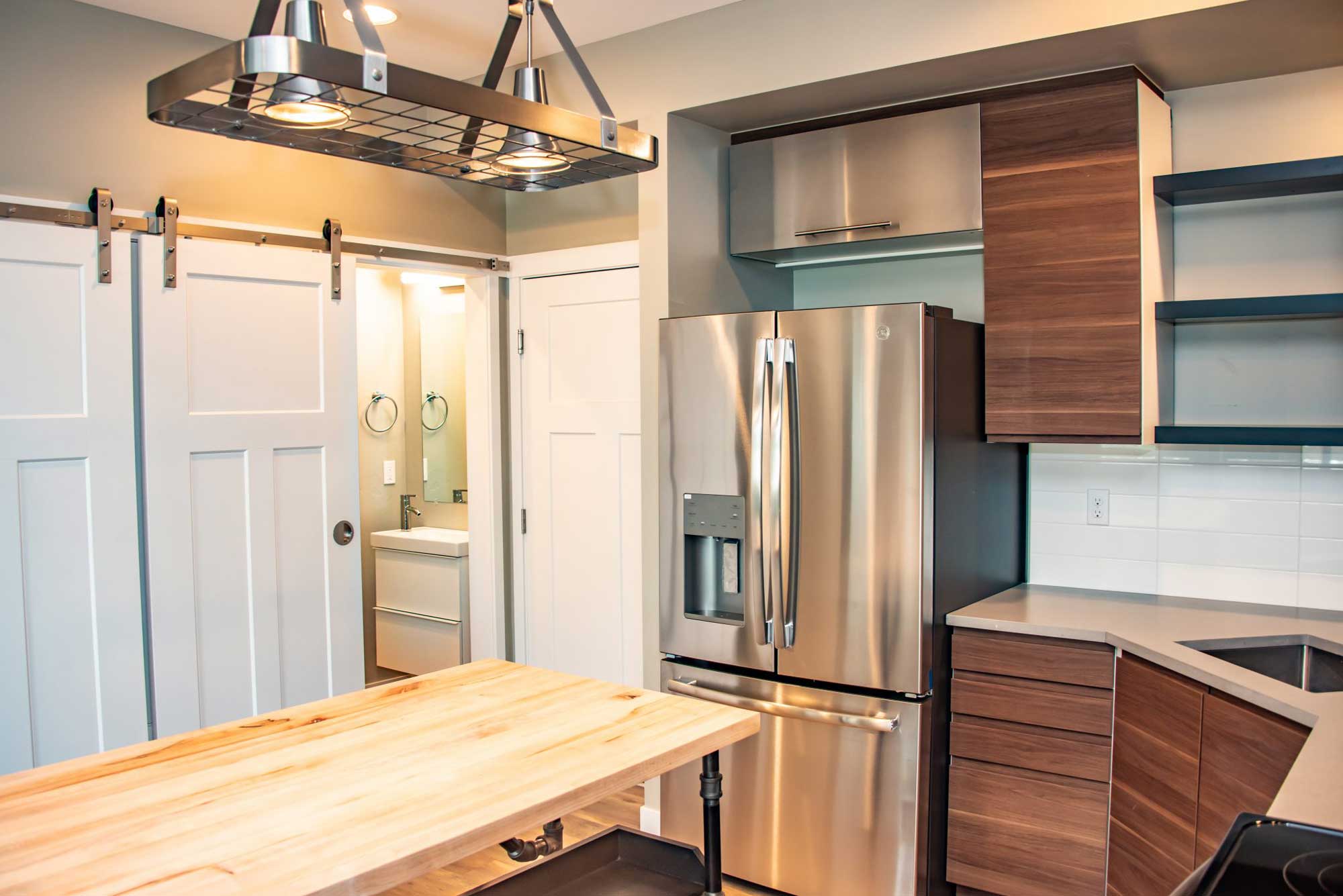Spacious kitchen featuring stainless steel refrigerator, wooden cabinets, and open shelving.