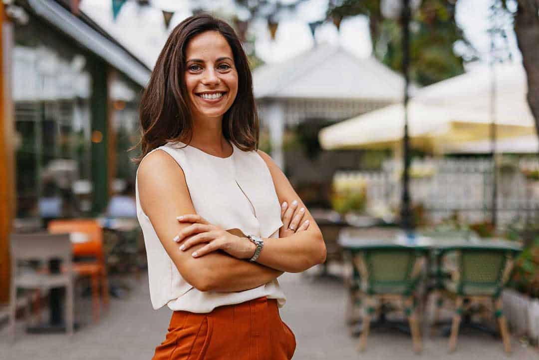 Confident female small business owner smiling outside her restaurant.