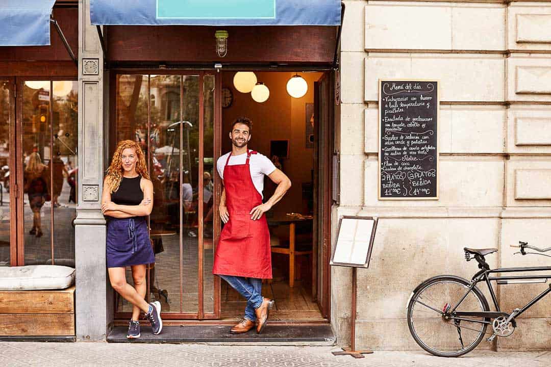 Two small business owners standing confidently outside their shop, representing SMEs supported by Redcurrant Services in London.
