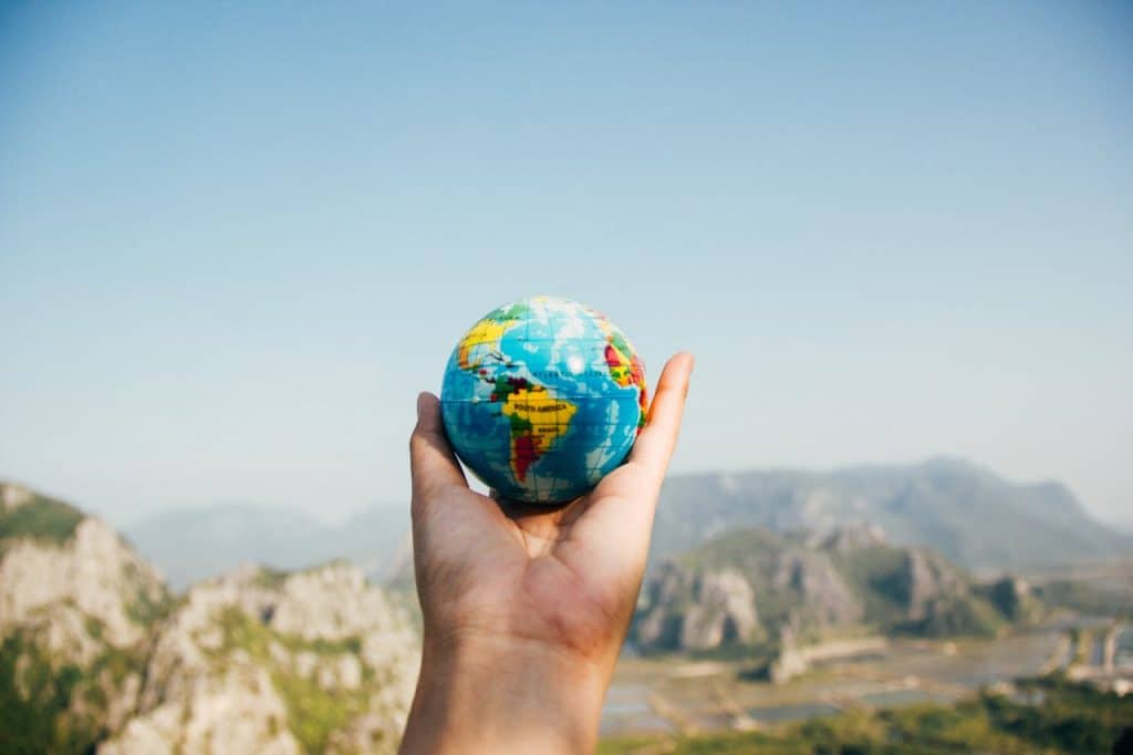 person-holding-world-globe-facing-mountain-346885