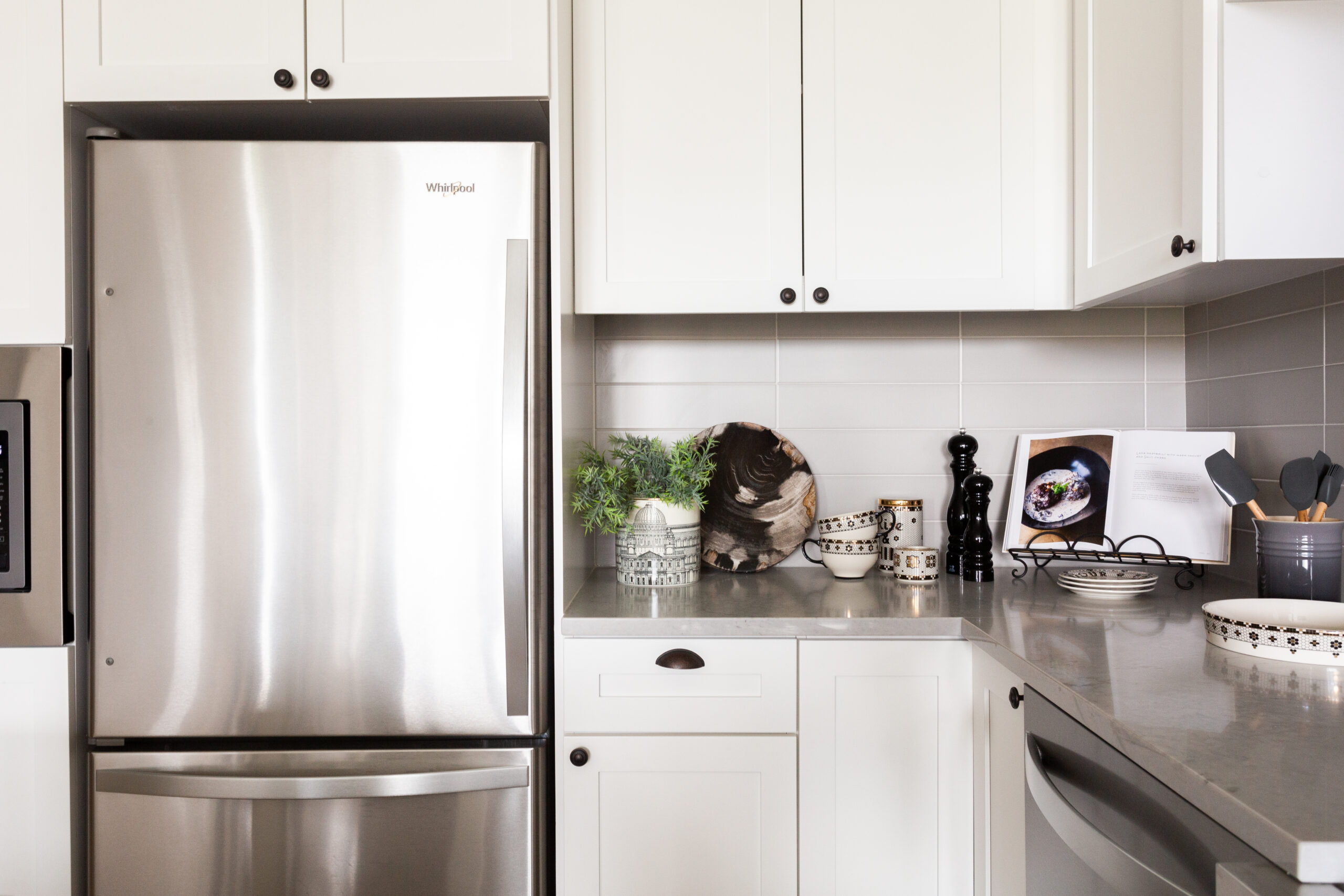 modern apartment kitchen with stainless steel refrigerator and white cabinets