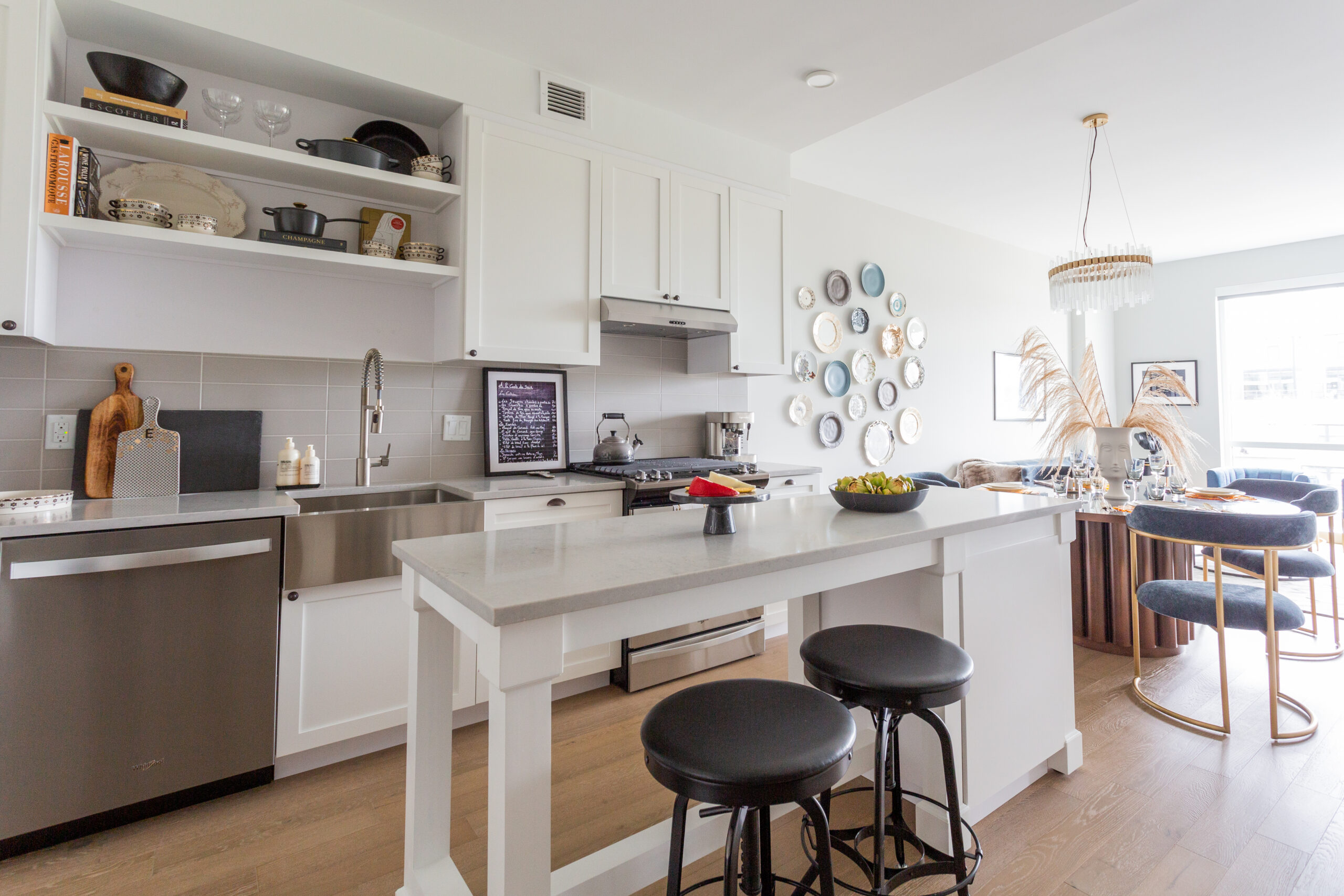 modern apartment kitchen with island, stainless steel appliances, white cabinets and gray tile backsplash