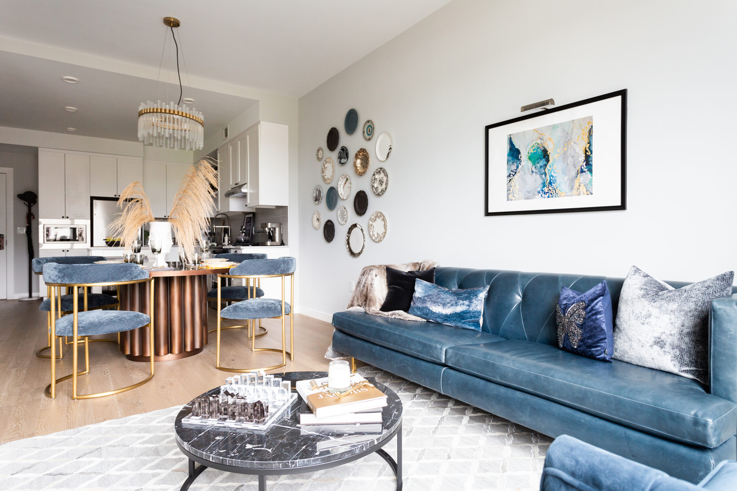 modern apartment interior with blue leather sofa, coffee table, dining table and chairs and kitchen in the background