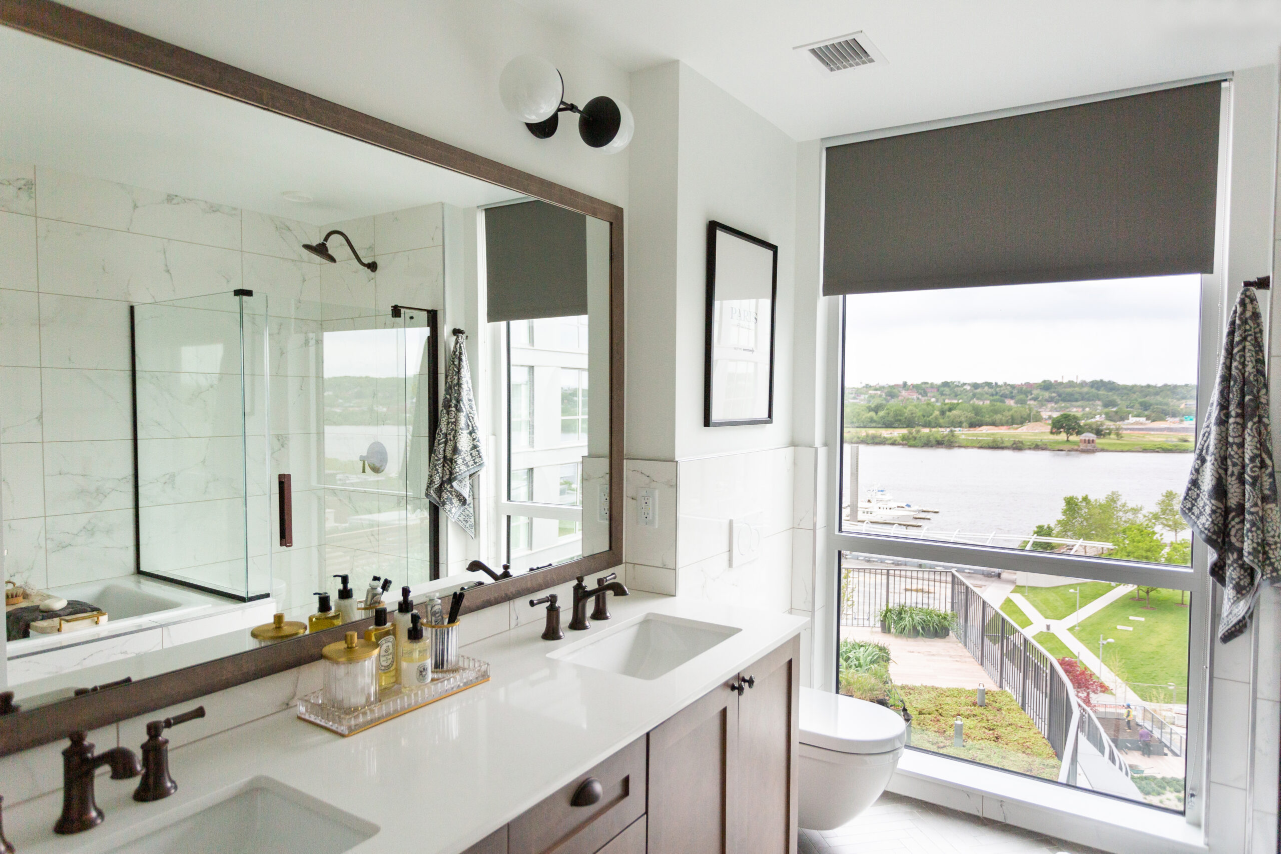 modern apartment bathroom with double vanity, large mirror, and large window
