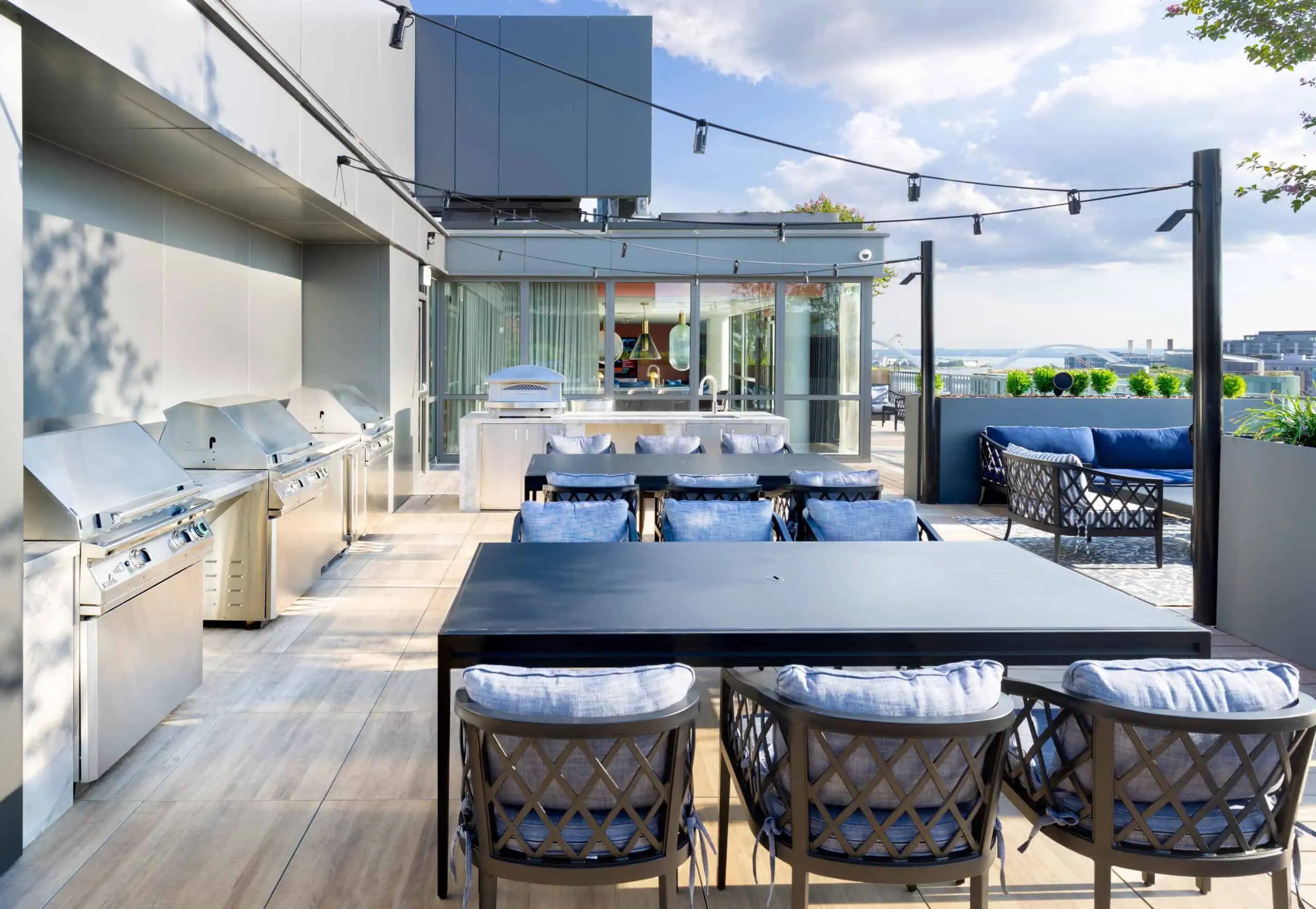 rooftop patio with grilling area, tables and chairs and other seating areas