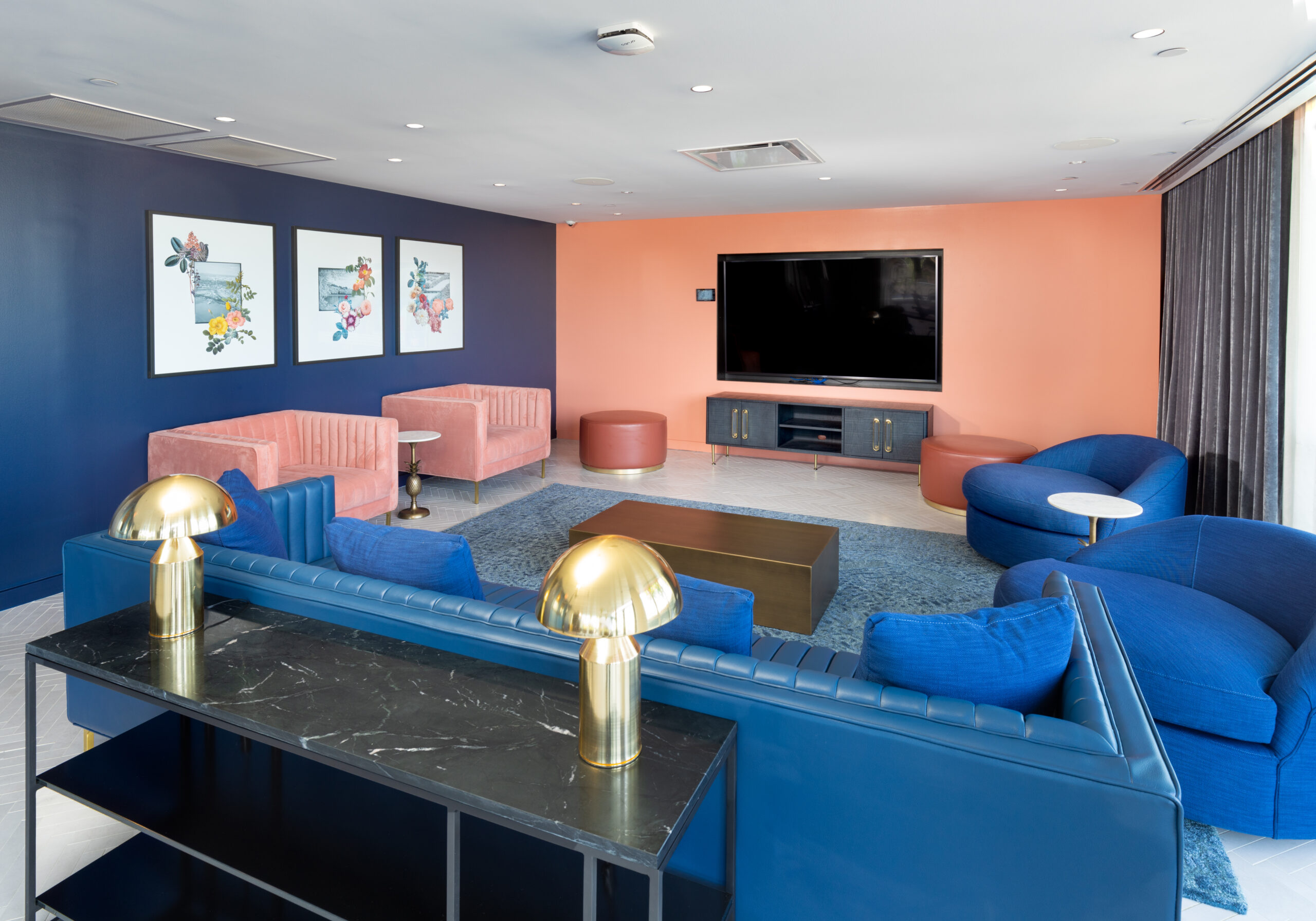 apartment lounge with blue leather sofa, blue and pink chairs and large flatscreen television