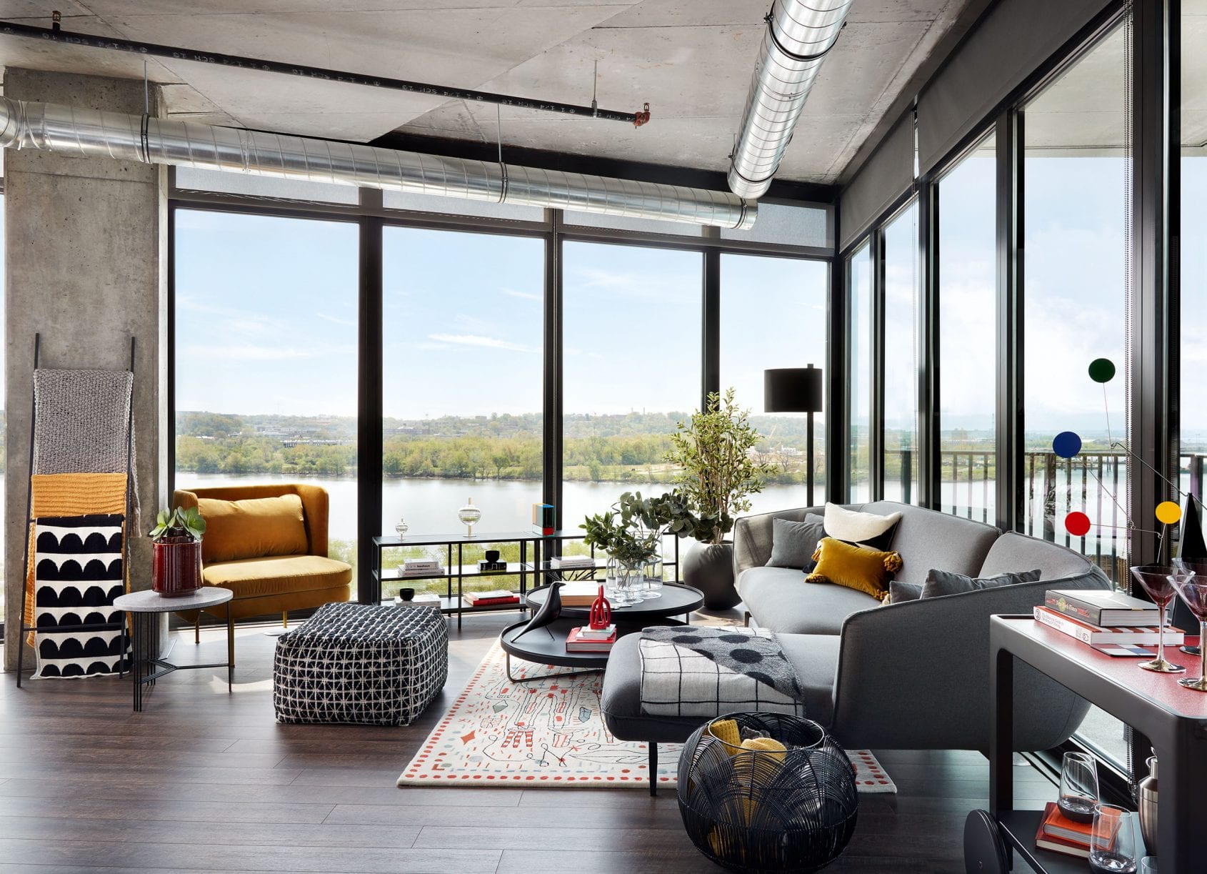 Living room with floor-to-ceiling windows, a cozy seating area, and river views.