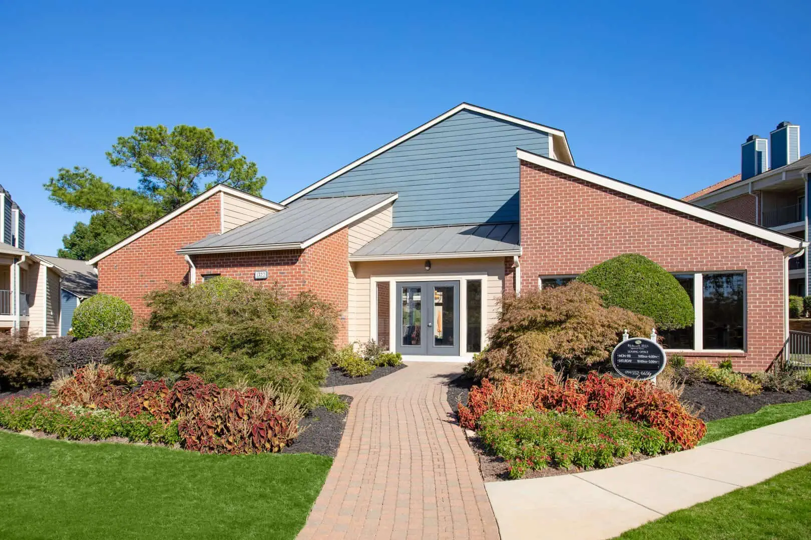 Exterior of an apartment leasing office with flowers in the foreground