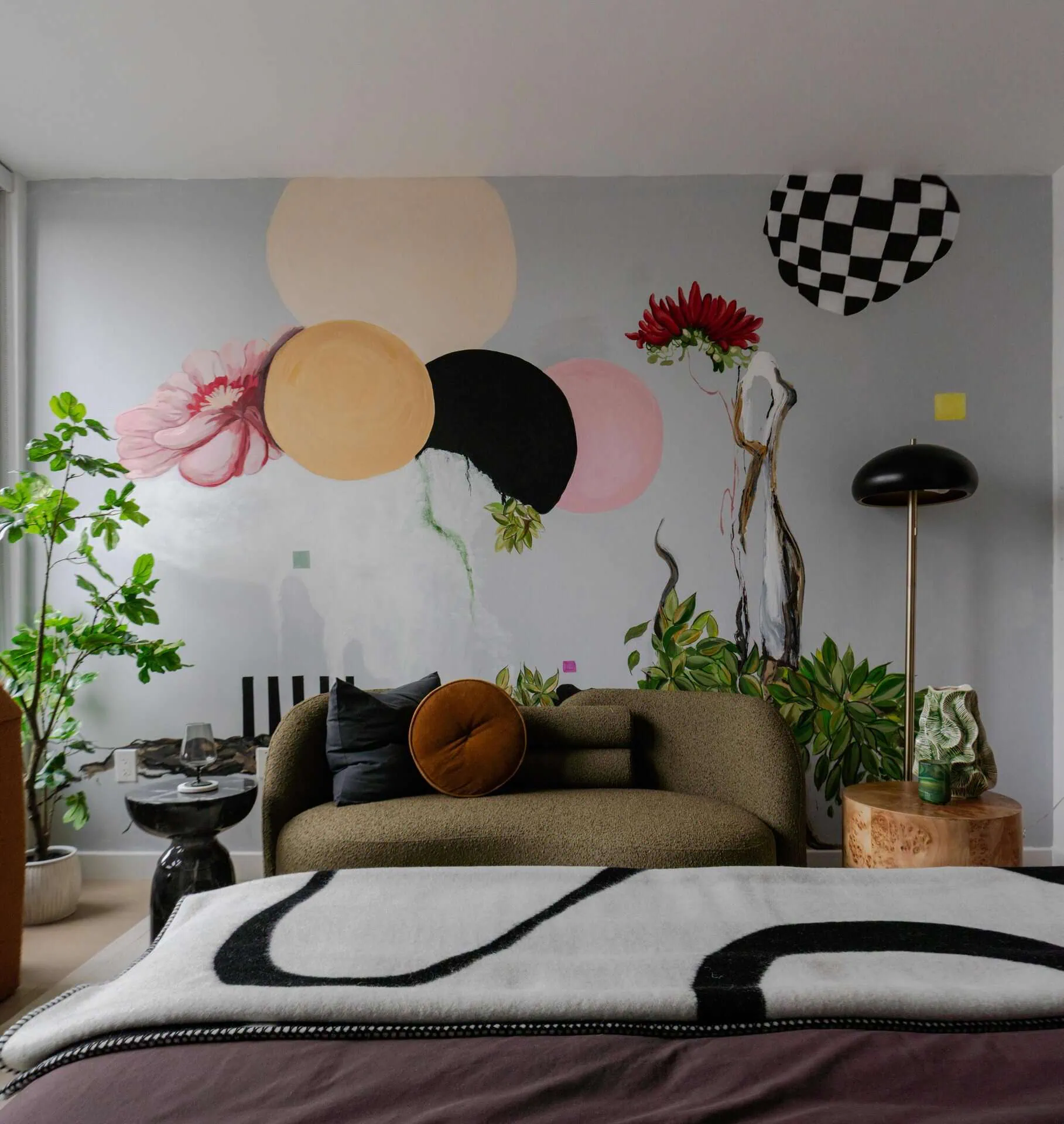 A bedroom with a large window and a colorful mural.