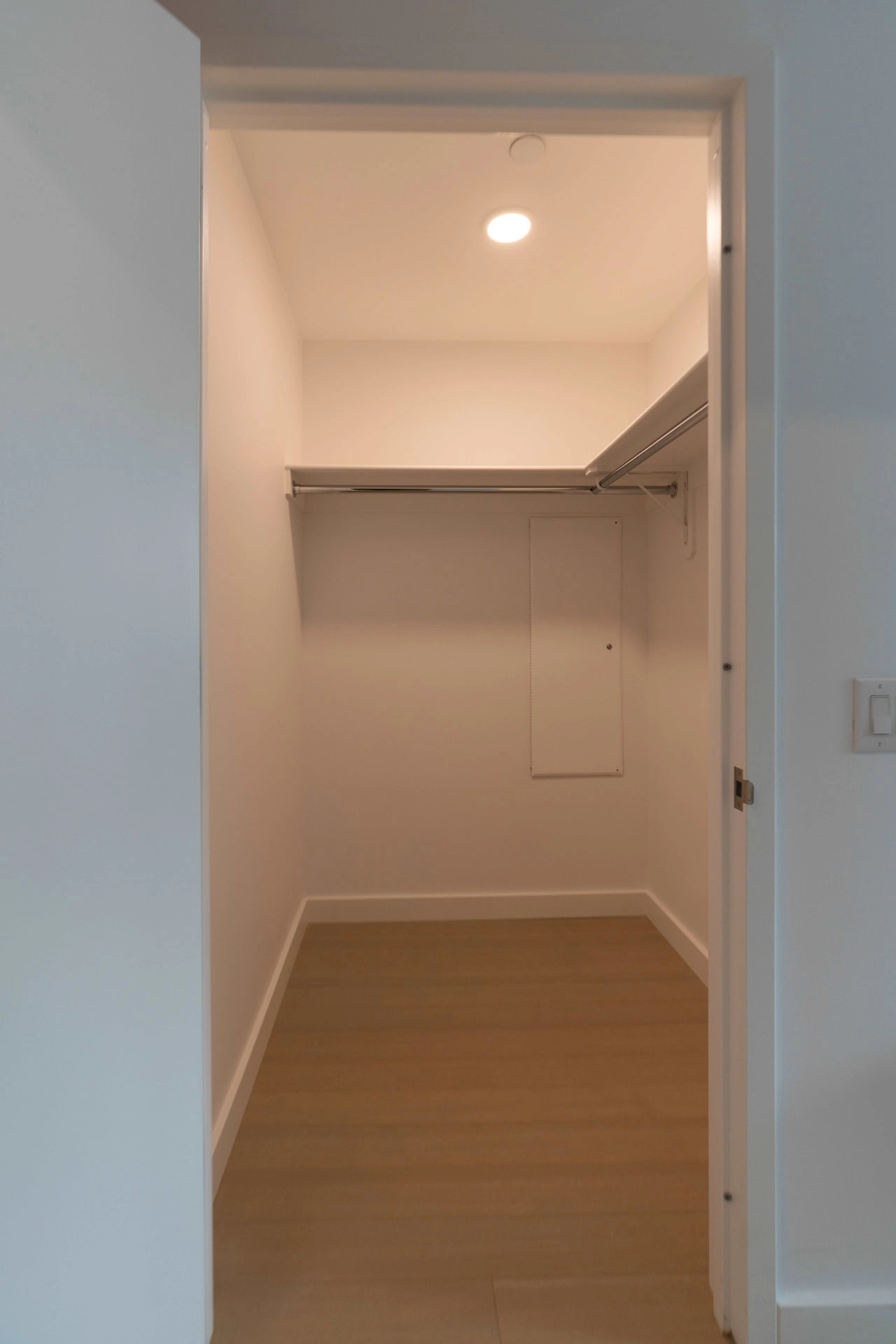 A closet with a door and a light switch.