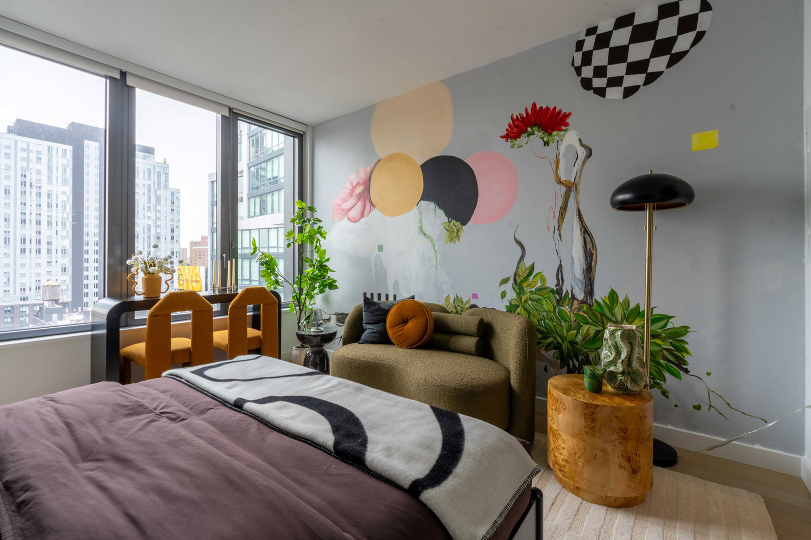 A bedroom with a large window and a colorful mural.