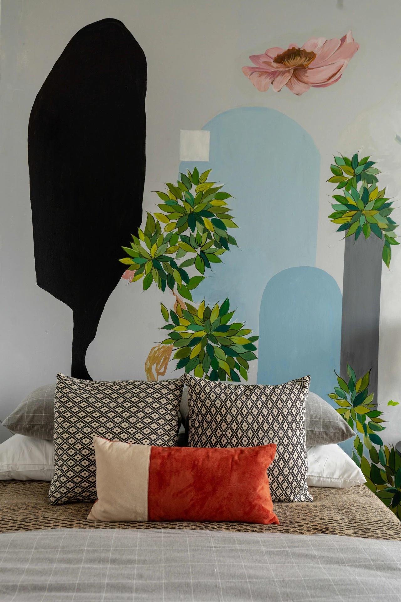 A bedroom with a large bed and a wall mural.