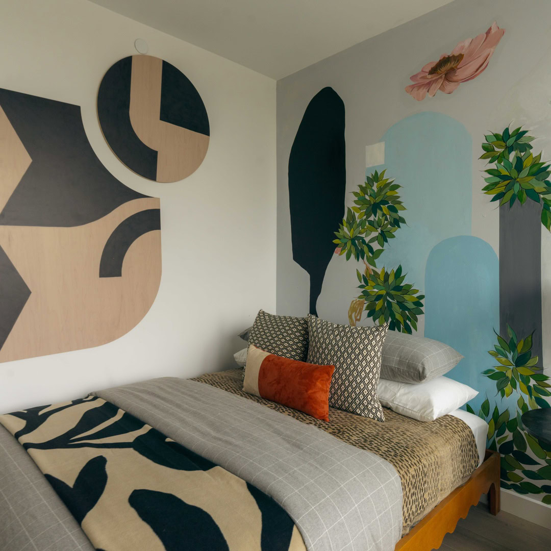 A bedroom with a large window and a mural on the wall.