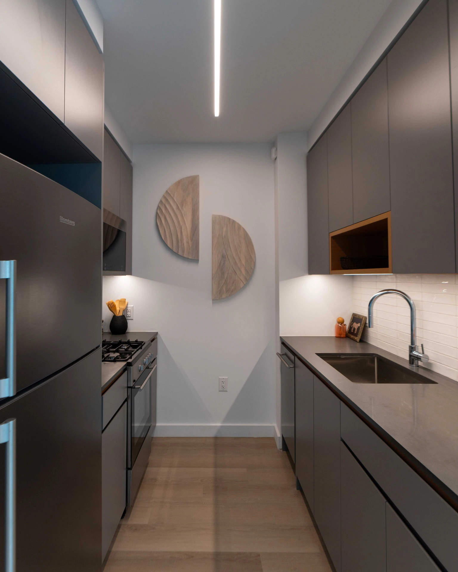 A modern kitchen with stainless steel appliances and wood floors.