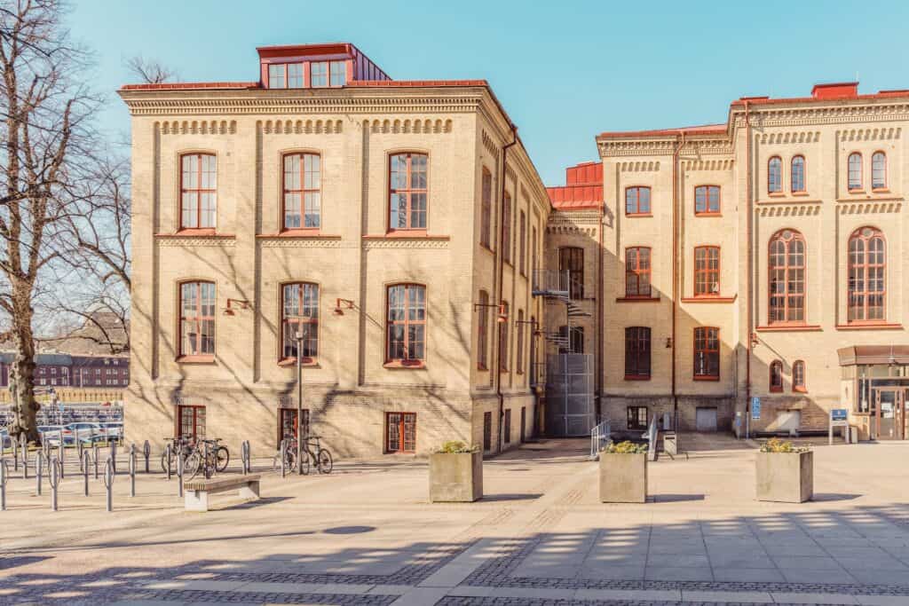 Gul tegelfasad med stora fönster och innergård vid Pedagogen i Göteborg