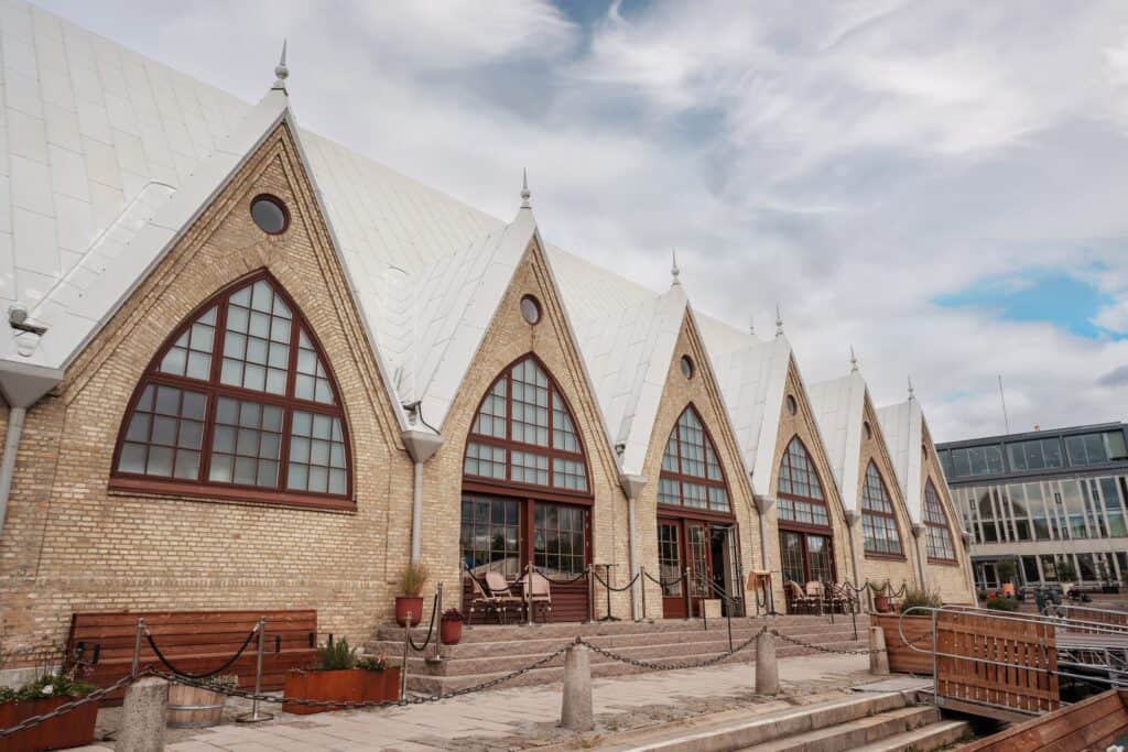 Historisk byggnad med stora fönster och tak i tegel, utomhusmiljö.