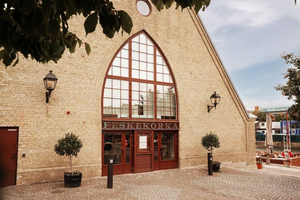 Restorio, Fiskekyrka i Stockholm, vacker byggnad med stora fönster och träd utanför.