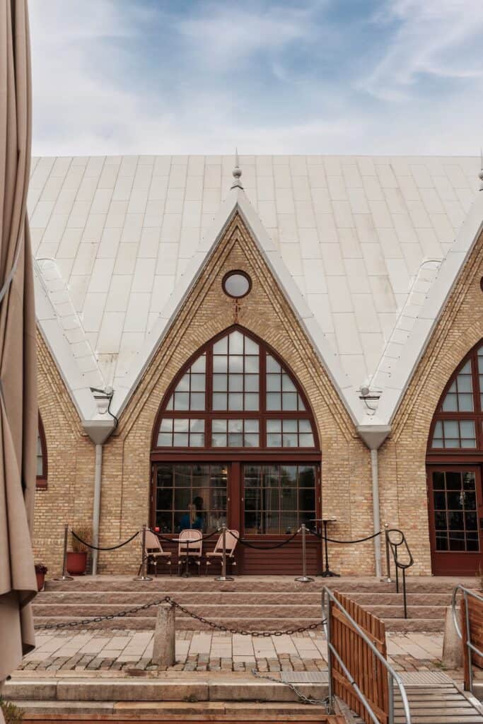 Kyrkobyggnad med stora fönster och brant tak, utomhusmiljö med trappsteg och staket.
