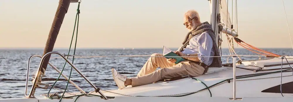 A man relaxing on a yacht reading a book as the sun rises in the morning