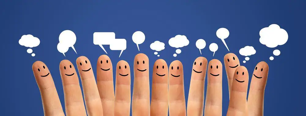 Fingers with smiley faces painted on and speech bubbles above them representing social media messages