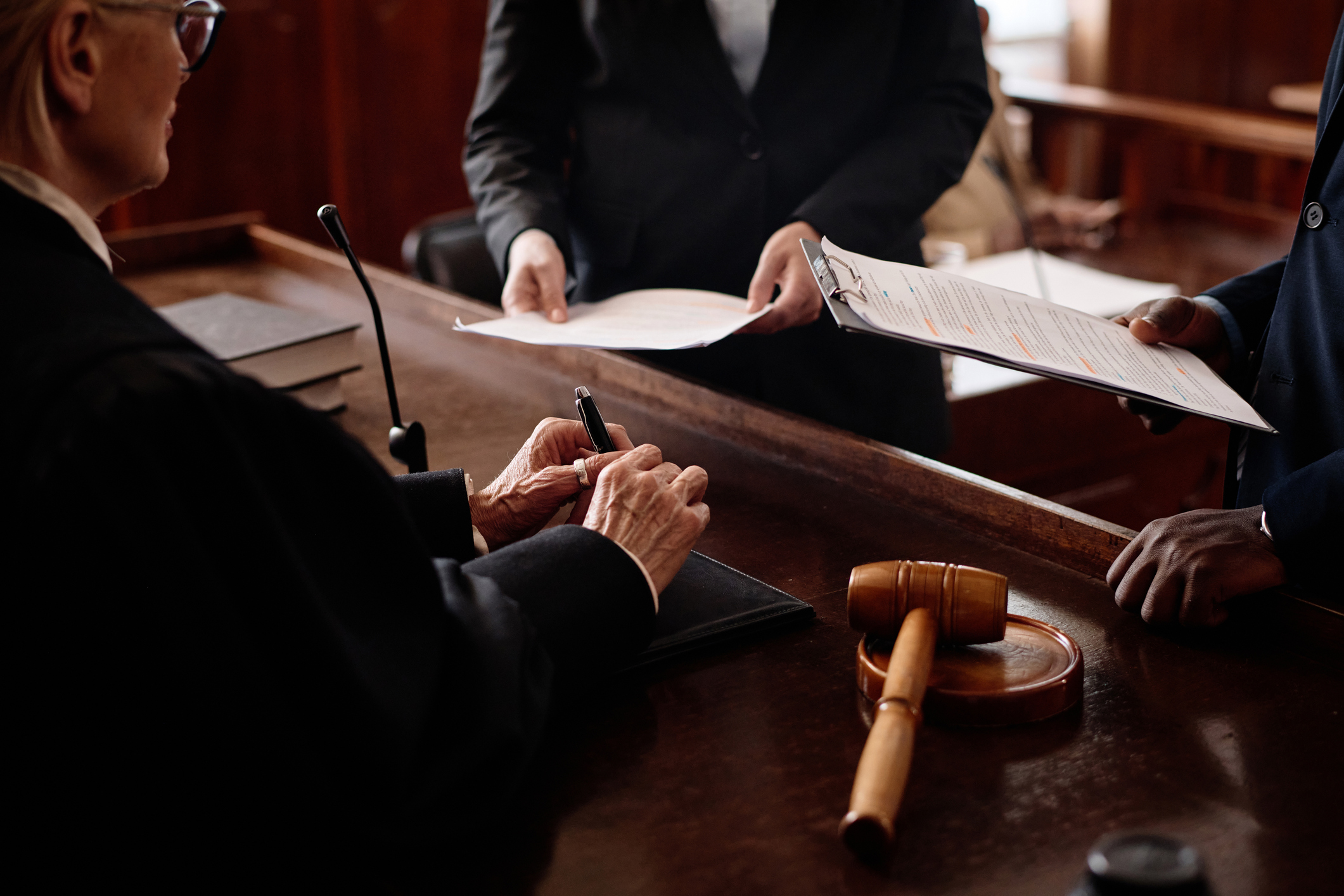 Close-up of accusation and protection sides with juridical documents standing in front of female judge during discussion of case points