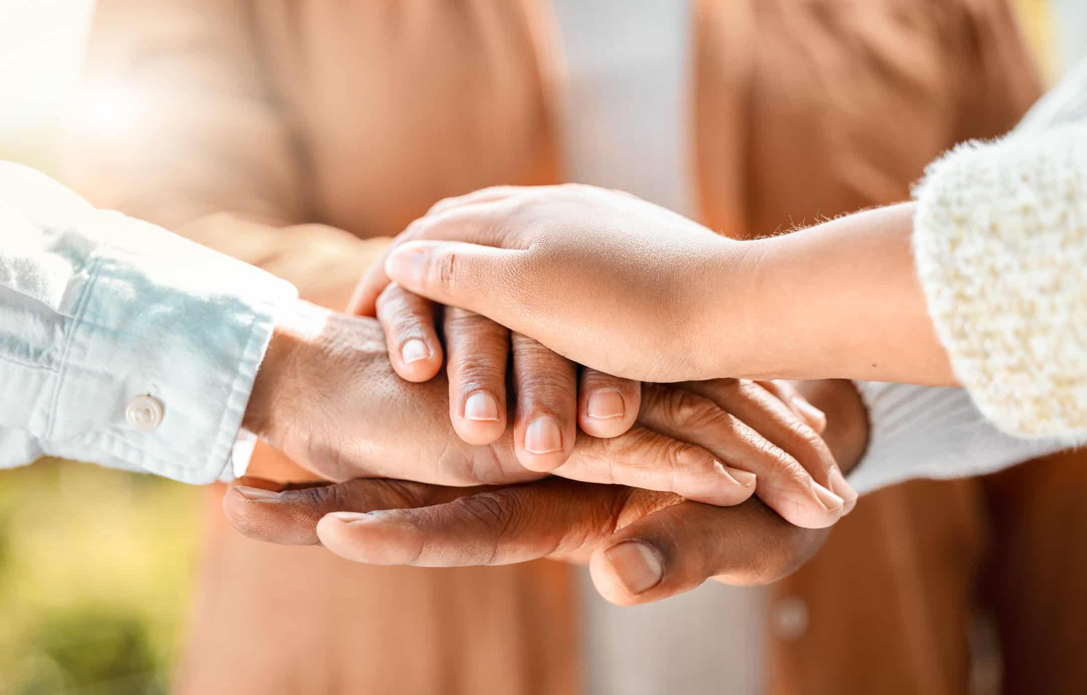 unrecognizable family of three with their hands in a pile outside