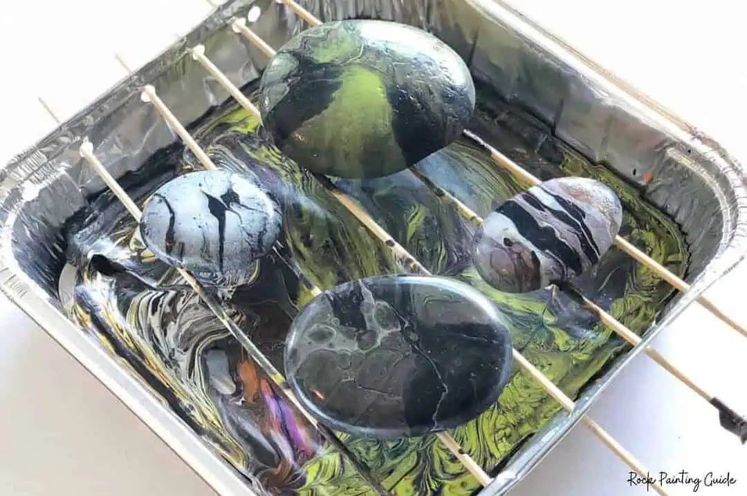 Halloween Paint Pouring on Rocks: Easy Acrylic Pour Tutorial 8 Halloween paint poured rocks drying on a DIY foil paint pouring tray